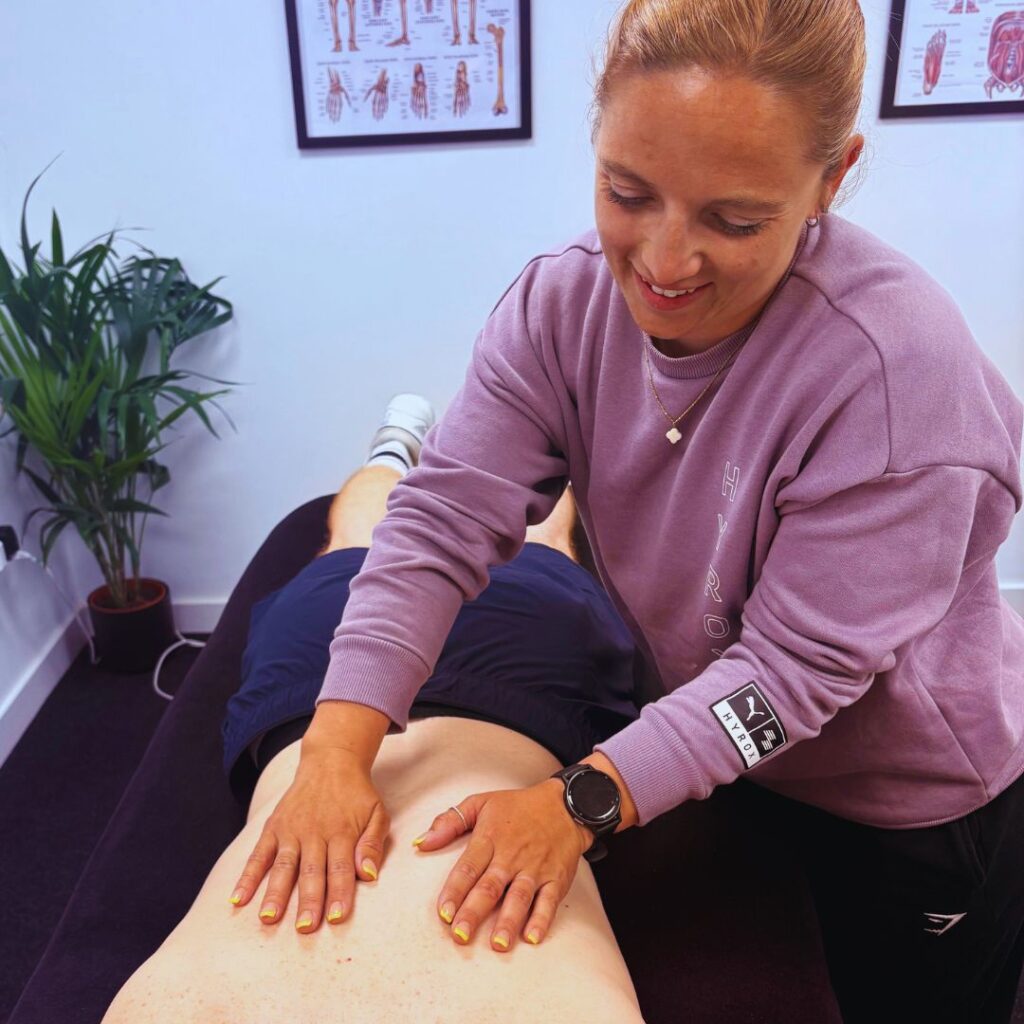Physiotherapist performing back massage on patient table.